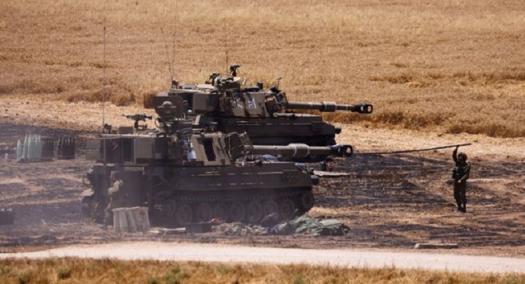 Israeli soldiers work at their artillery unit near the border between Israel and the Gaza Strip, on its Israeli side
